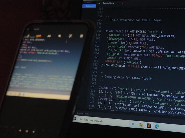 SQL code displayed on a tablet and computer in a darkened room